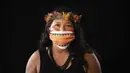 Terezinha de Souza (45) dari kelompok etnis pribumi Sateré Mawé mengenakan pakaian tradisional sukunya dan masker saat pandemi virus corona COVID-19 di daerah Gaviao, dekat Manaus, Brasil, Jumat (29/5/2020). Pada akhir Mei, dia jatuh sakit dengan tanda-tanda terpapar COVID-19. (AP Photo/Felipe Dana)
