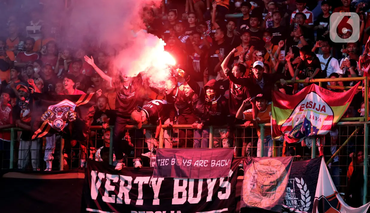 Suporter menyalakan flare saat menyaksikan laga Persija melawan Sabah FC pada laga uji coba internasional di Stadion Patriot Candrabhaga, Kota Bekasi, Minggu (5/6/2022). Pertandingan sepakbola kembali bisa disaksikan secara langsung setelah pemerintah melonggarkan aturan pemakaian masker di luar ruangan. (Liputan6.com/Helmi Fithriansyah)