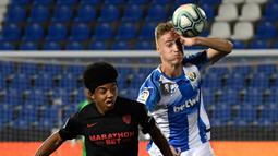 Bek Sevilla, Jules Kounde, berebut bola dengan striker Leganes, Manu Garrido, pada laga lanjutan La Liga pekan ke-33 di Estadio Municipal de Butarque, Rabu (1/7/2020) dini hari WIB. Sevilla menang 3-0 atas Leganes. (AFP/Pierre-Philippe Marcou)