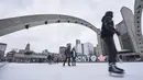 Orang-orang berseluncur es di arena luar ruangan di Nathan Phillips Square di Toronto, Ontario, Rabu (5/1/2022). Provinsi Ontario menutup semua arena dalam ruangan serta pusat kebugaran lainnya di tengah kesibukan pembatasan baru guna membendung penyebaran varian Omicron Covid-19. (Geoff Robins/AFP)