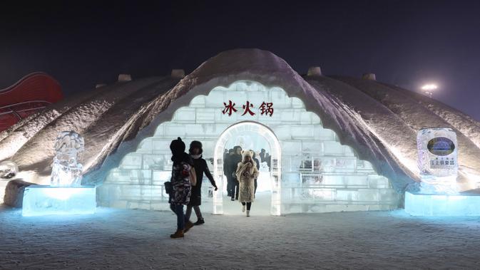 Foto yang diambil 13 Januari 2020, orang-orang keluar dari iglo seusai menikmati hot pot di meja dan kursi berukir es selama Festival Es dan Salju Internasional Harbin tahunan. Restoran berbentuk rumah salju bangsa Eskimo ini hadir untuk memberikan sensasi makan malam yang berbeda. (STR/AFP)