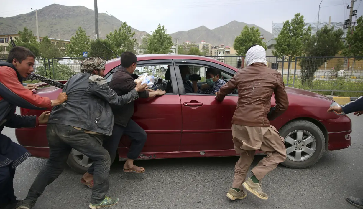 Warga berebut mendapatan makanan berbuka puasa gratis yang disumbangkan oleh sukarelawan selama bulan puasa suci Ramadan di Kabul, Afghanistan, Kamis (7/5/2020). Muslim di seluruh dunia melewati Ramadan tahun ini di tengah pandemi virus corona COVID-19 dan PHK. (AP Photo/Rahmat Gul)