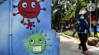 Warga yang mengenakan masker berjalan melintasi mural berisi imbauan terkait COVID-19 di Menteng, Jakarta, Kamis (7/10/2021). Pemerintah menyiapkan langkah implementasi prokes 3M, implementasi surveilans 3T, percepatan vaksinasi dan persiapan fasilitas rumah sakit. (Liputan6.com/Johan Tallo)