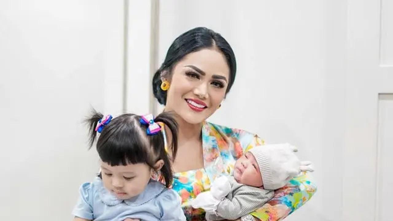 Krisdayanti elegan dalam kebaya dan batik, menggendong kedua cucunya.