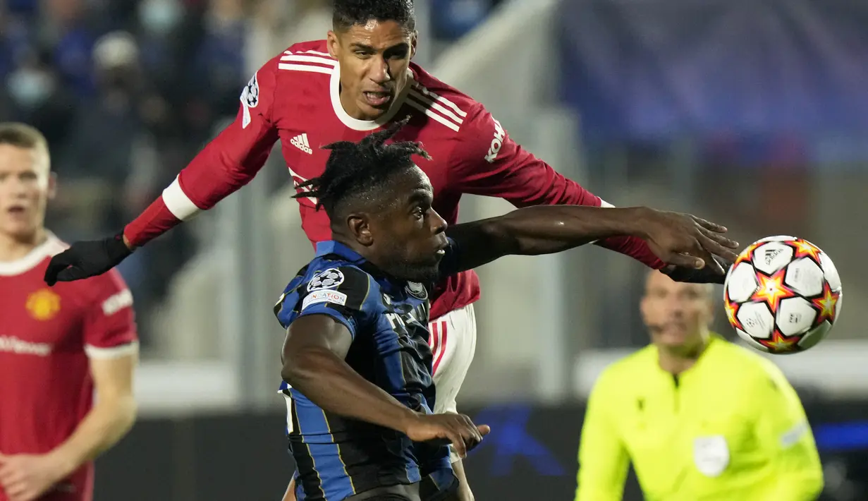 Penyerang Atalanta, Duvan Zapata berebut bola dengan bek Manchester United (MU), Raphael Varane pada matchday keempat Liga Champions di Stadion Gewiss, Rabu dini hari WIB (3/11/2021). Atalanta berhasil menahan imbang MU 2-2. (AP Photo/Luca Bruno)
