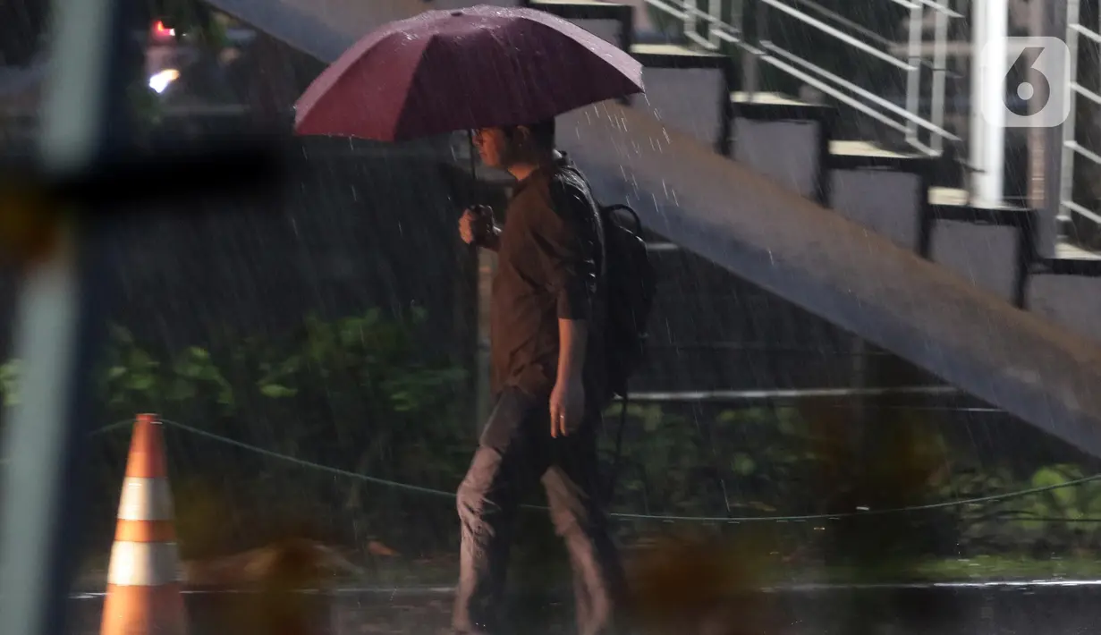 Warga menggunakan payung saat melintas di kawasan Kuningan, Jakarta, Selasa (8/11/2022). Curah hujan yang tinggi di kawasan Jakarta berpotensi menimbulkan genangan atau banjir sehingga berpotensi memicu kemacetan, terutama saat jam kerja. (Liputan6.com/Helmi Fithriansyah)