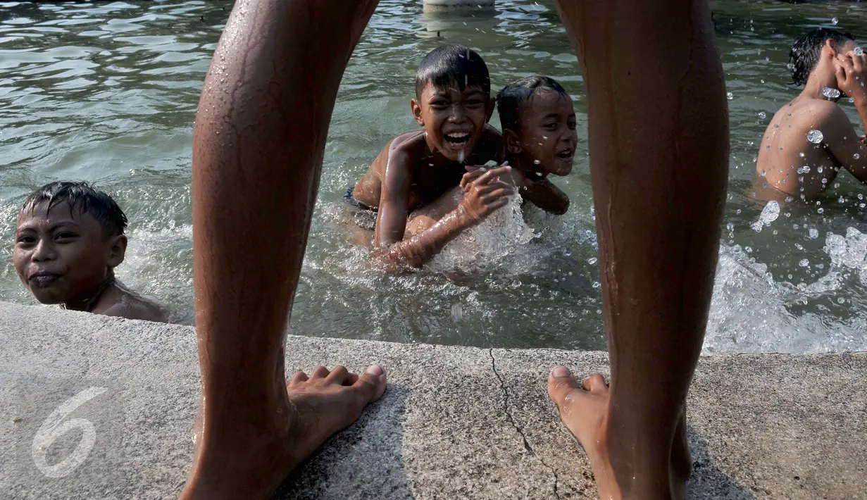 Sejumlah anak asik berenang dan bermain di kolam air mancur di kawasan Jalan Diponogoro, Jakarta, Jumat (31/7/2015). Minimnya lahan bermain di Ibukota, membuat mereka memanfaatkan kolam air mancur sebagai tempat berenang. (Liputan6/Johan Tallo)