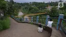 Anak-anak bersantai dekat jembatan gantung Kuning yang menghubungkan Pasar Minggu Poltangan ke Cililitan Condet, Jakarta, Selasa (28/12/2021). Jembatan gantung dengan panjang 40 meter di atas sungai Ciliwung tersebut baru baru ini dijadikan lokasi foto untuk konten medsos. (merdeka.com/Imam Buhori)