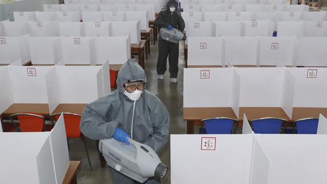 Para pekerja mengenakan alat pelindung diri saat mendisinfeksi kafetaria sebuah sekolah menengah di Gwangju, Korea Selatan, Selasa (19/5/2020). Sekolah-sekolah di Korea Selatan secara bertahap akan mulai dibuka pada 20 Mei 2020. (Park Chul-hong/Yonhap via AP)