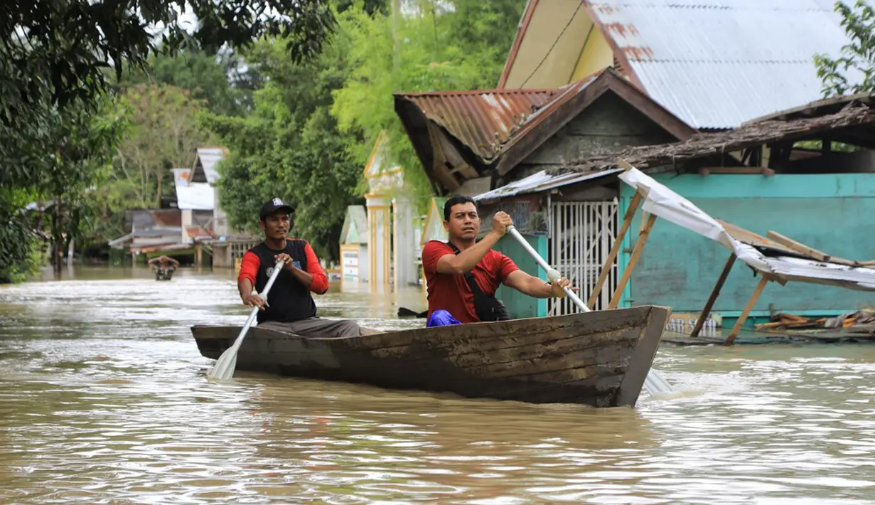 Warga mendayung perahu kayu saat banjir di Lhoksukon, Aceh Utara, Aceh, 3 Januari 2022. Berdasarkan data Badan Penanggulangan Bencana Daerah (BPBD) Aceh Utara, banjir mengakibatkan 2.278 jiwa terdampak dan satu orang anak meninggal dunia. (AZWAR IPANK/AFP)
