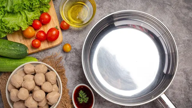 Sebuah panci berbahan tembaga di samping bahan-bahan makanan (Foto Dok: Freepik/jcomp)