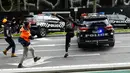 Demonstran menendang mobil polisi selama protes terhadap peraturan Covid-19 di Melbourne (21/9/2021). Ribuan orang membuat kekacauan dan bentrok dengan polisi di kota dan mengambil alih jalan raya utama Melbourne saat protes terjadi. (AFP/STR)