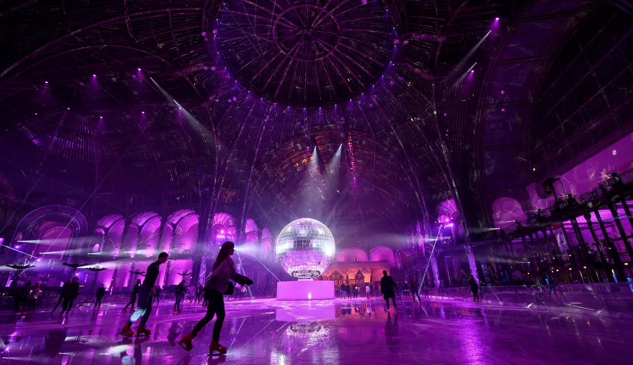 Orang-orang berseluncur di arena ice skating di bawah kubah kaca mewah legendaris, Grand Palais, Paris, Selasa (17/12/2019). Aren seluncur es musiman ini terbuka untuk umum selama liburan Natal. (Photo by Thomas SAMSON / AFP)