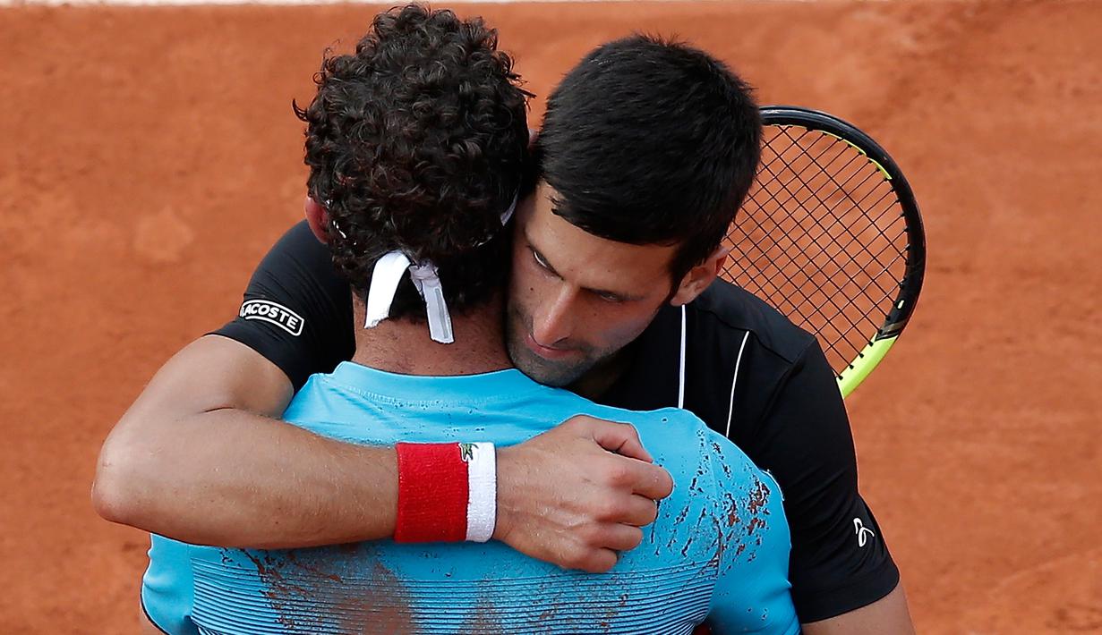 Petenis Serbia, Novak Djokovic memeluk petenis Italia Marco Cecchinato seusai perempatfinal Prancis Terbuka 2018 di stadion Roland Garros, Selasa (5/6). Djokovic tumbang 3-6, 6-7, 6-1, dan 6-7 dalam waktu 3 jam 26 menit. (AP Photo/Michel Euler)