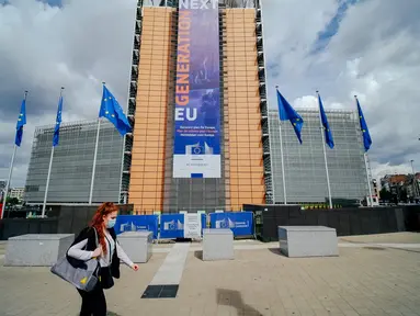 Seorang wanita yang mengenakan masker berjalan melewati markas Komisi Eropa di Brussel, Belgia, Selasa (7/7/2020). Komisi Eropa memprediksi Ekonomi Eropa akan menghadapi resesi lebih dalam akibat langkah-langkah pengendalian COVID-19 yang berkepanjangan. (Xinhua/Zhang Cheng)