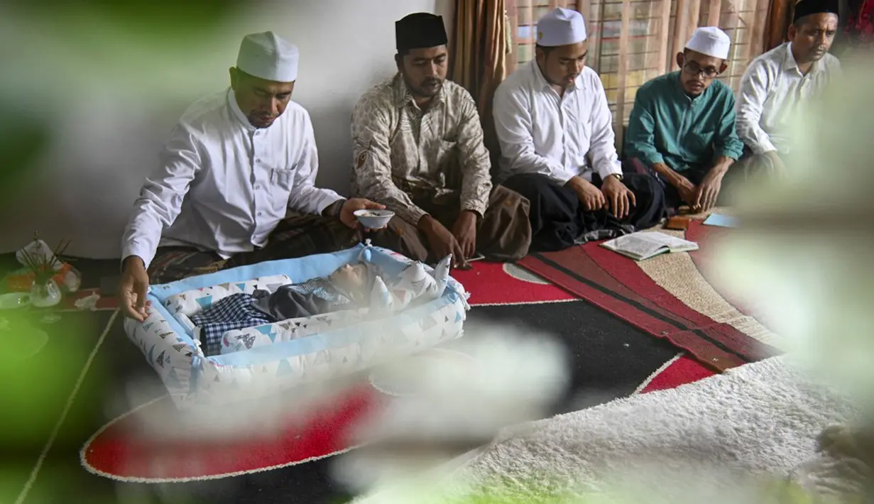 Orang-orang berdoa untuk bayi yang baru lahir saat prosesi aqiqah di Banda Aceh, Aceh, 4 November 2021. Aqiqah adalah tradisi menyambut bayi yang baru lahir dalam agama Islam. (CHAIDEER MAHYUDDIN/AFP)