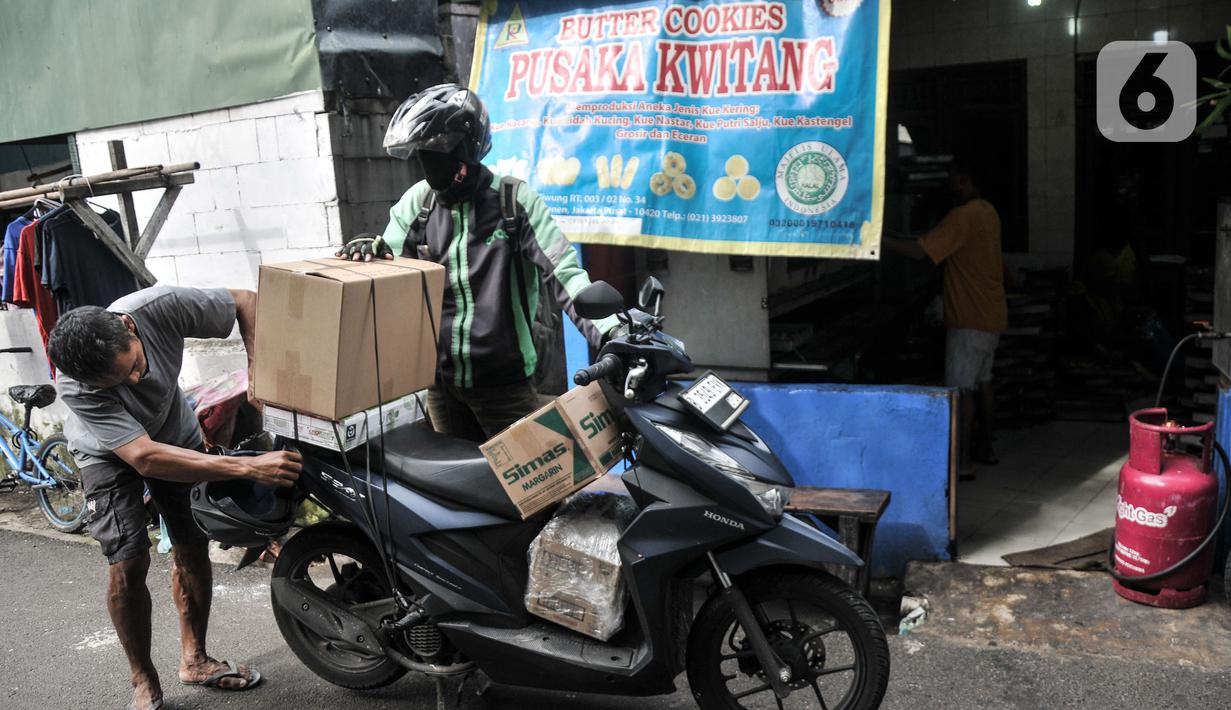 Pekerja menata produksi kue kering ke atas motor untuk diberikan kepada pelanggan di industri rumahan Pusaka Kwitang, Jakarta, Kamis (6/4/2023). (merdeka.com/Iqbal S Nugroho)