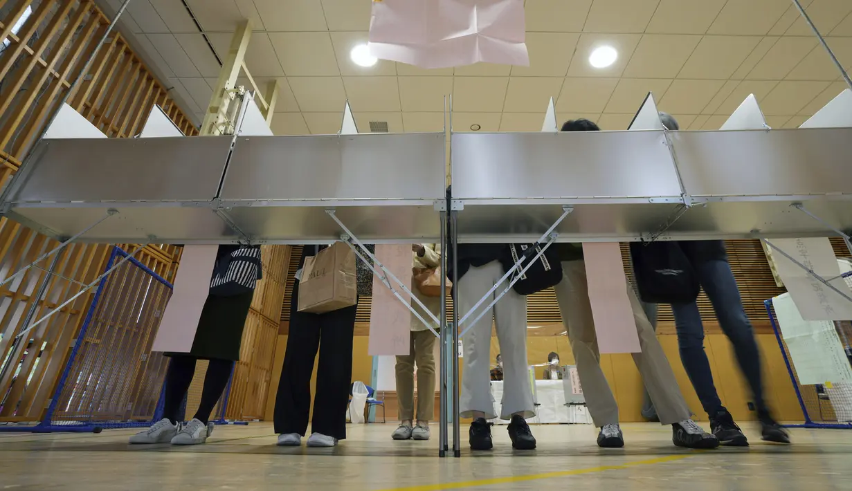 Para pemilih bersiap untuk memberikan suara mereka dalam pemilihan majelis rendah saat perwakilan dari komisi administrasi pemilihan lokal mengamati di sebuah TPS, Tokyo, Jepang, Minggu (31/10/2021). Jepang menggelar Pemilu di tengah pandemi COVID-19. (AP Photo/Eugene Hoshiko)