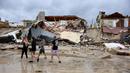 Penduduk melewati rumah-rumah yang sebagian roboh ke pantai setelah Badai Nicole mendarat di Pantai Daytona, Florida (10/11/2022). Badai Nicoler datang ke darat sebagai badai Kategori 1 sebelum melemah menjadi badai tropis saat bergerak melintasi negara bagian. (Joe Raedle/Getty Images/AFP)