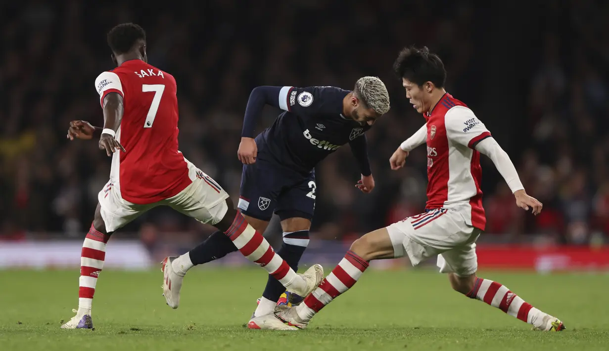 Penyerang West Ham United Said Benrahma (tengah) berebut bola dengan pemain Arsenal Takehiro Tomiyasu dan Bukayo Saka dalam laga pekan 17 Liga Inggris di Emirates Stadium, Kamis dini hari WIB (16/12/2021). Arsenal sukses kalahkan tamunya West Ham dengan skor 2-0. (AP Photo/Ian Walton)