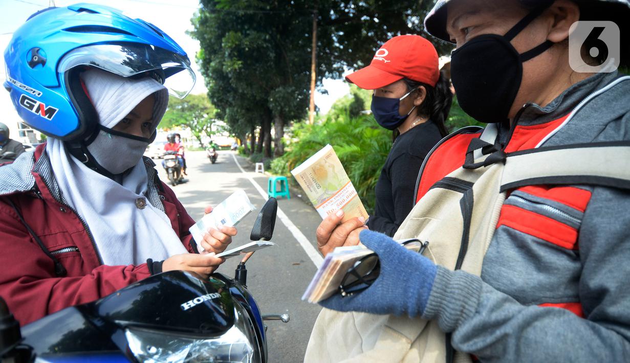 Pengguna jalan membeli uang baru yang dijajakan penjual jasa penukaran uang di kawasan Bintaro Sektor 2, Jakarta Selatan, Selasa (12/05/2020). Menjelang perayaan Lebaran, jasa penukar uang keliling yang berada di pinggir jalan-jalan utama mulai bermunculan. (merdeka.com/Dwi Narwoko)