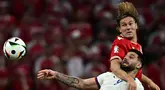 Penyerang Serbia #09 Aleksandar Mitrovic (Kiri) melompat untuk mengejar bola dengan bek Denmark #02 Joachim Andersen dalam matchday terakhir Grup C Euro 2024 di Allianz Arena, Rabu (26/6/2024) dini hari WIB. (Tobias SCHWARZ / AFP)
