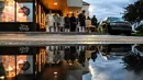 Refleksi pria Muslim terlihat dari genangan air saat mereka salat di trotoar di luar restoran selama bulan suci Ramadhan di Lauderhill, Florida, Jumat (30/4/2021). Selama puasa Ramadhan, umat Islam tidak makan, minum, atau aktivitas seksual dari fajar hingga matahari terbenam. (CHANDAN KHANNA/AFP)