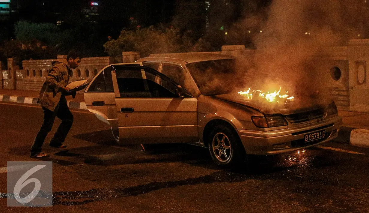 Pemilik mobil berusaha menyelamatkan barang miliknya saat mobil terbakar di jalan layang Latuharhari, Jakarta, Kamis (18/9/2015). Diduga kebakaran akibat konsleting listrik yang terjadi dibagian depan kap mobil. (Liputan6.com/Faizal Fanani)