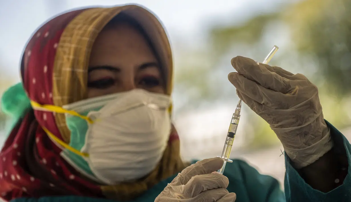 Seorang dokter bersiap untuk memberikan vaksin virus corona COVID-19 Sinovac di klinik vaksinasi massal darurat di lapangan sepak bola di Surabaya, Jawa Timur, Selasa (6/7/2021). Indonesia tengah memerangi gelombang infeksi baru yang belum pernah terjadi sebelumnya. (JUNI KRISWANTO/AFP)