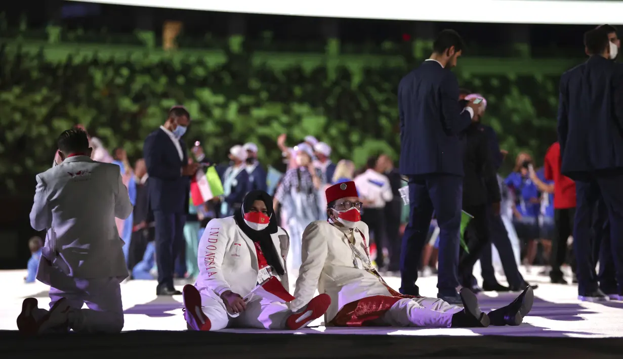 Kontingen Indonesia terlihat duduk saat upacara pembukaan Olimpiade Tokyo 2020 di Stadion Nasional Jepang, Tokyo, Jumat malam (23/7/2021). Mereka semua memakai masker merah putih, sesuai warna bendera Indonesia. (Hannah McKay/Pool Photo via AP)
