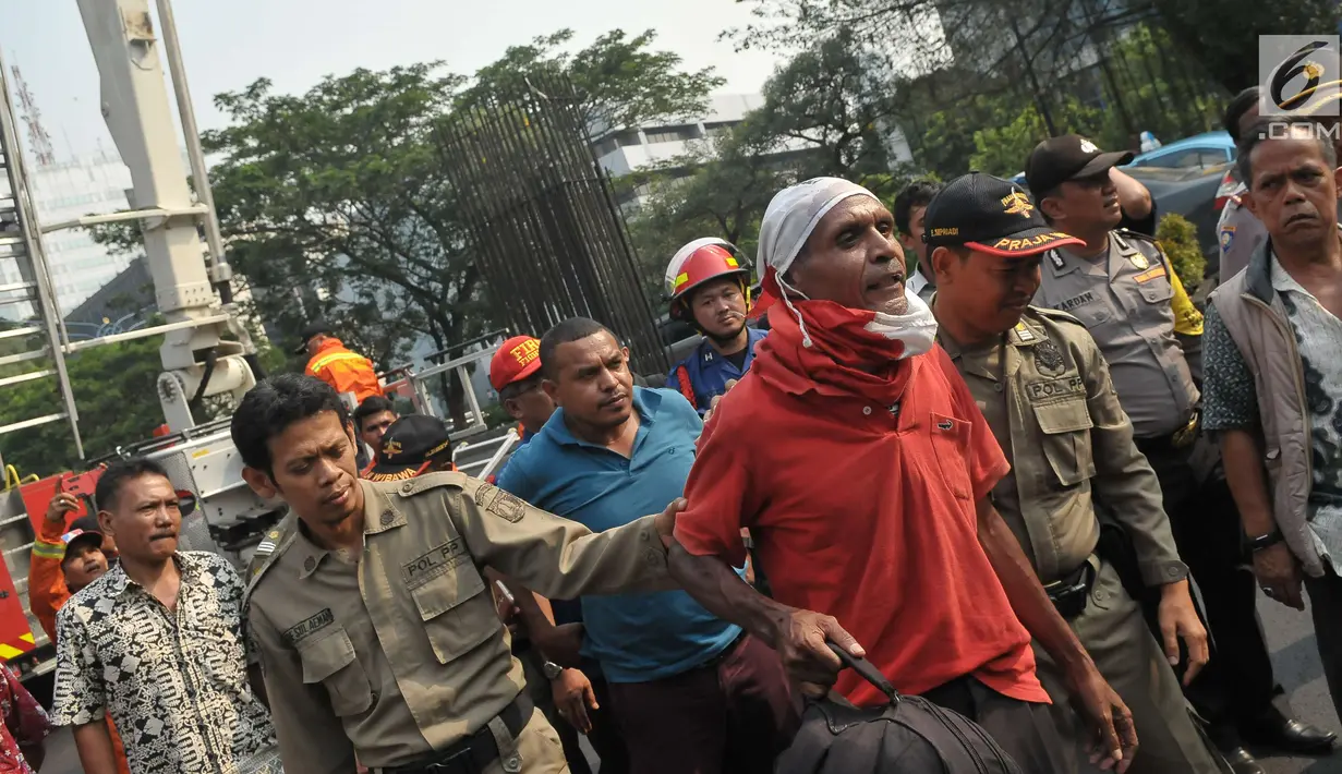 Petugas membawa Agustinus Woro usai turun dari baliho di seberang Kantor Pelayanan Pajak Pratama Setiabudi Satu, Jakarta, Jumat (26/5). Sebelum turun, Agustinus minta dipanggilkan pengacaranya dan dibelikan nasi padang. (Liputan6.com/Helmi Afandi)