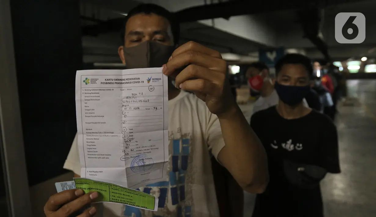 Seorang pedagang menunjukkan surat vaksinasi COVID-19 di Pasar Tanah Abang Blok A, Jakarta, Rabu (17/2/2021). Vaksinasi COVID-19 tahap kedua yang diberikan untuk pekerja publik dan lansia itu dimulai dari pedagang Pasar Tanah Abang di blok A, B, F, dan G. (Liputan6.com/Herman Zakharia)