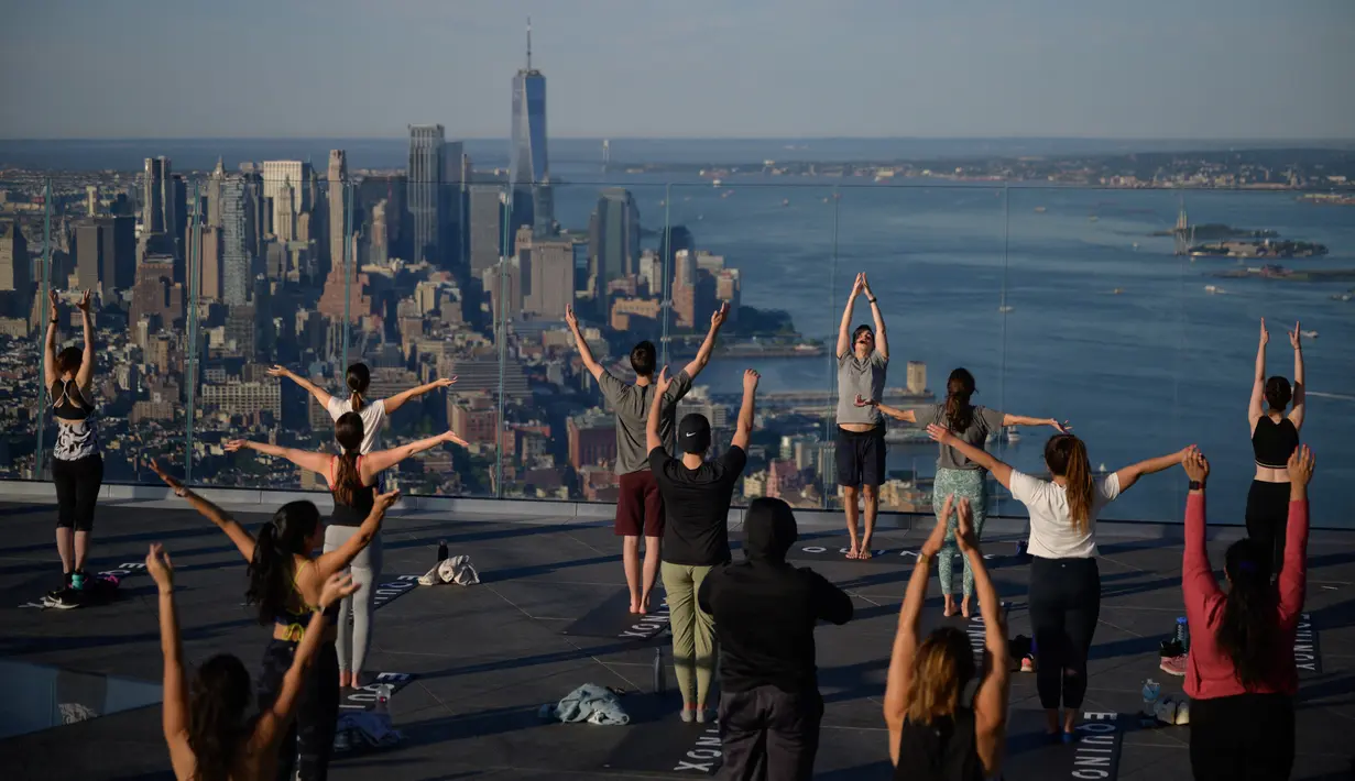 Praktisi yoga menghadiri kelas di Edge Observation Deck, Manhattan, New York, Amerika Serikat, Kamis (17/6/2021). Edge Observation Deck disebut sebagai 'dek langit luar ruang tertinggi di Belahan Barat'. (Ed JONES/AFP)