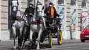 Pengemudi kereta kuda berputar di persimpangan di distrik ke-3 di Wina, Austria pada 8 April 2020. Kereta yang disebut Fiaker yang biasanya mengangkut turis berkeliling, kini semenjak pandemi Corona beralih fungsi menjadi pengantar makanan untuk warga lanjut usia di daerah tersebut. (ALEX HALADA/AFP