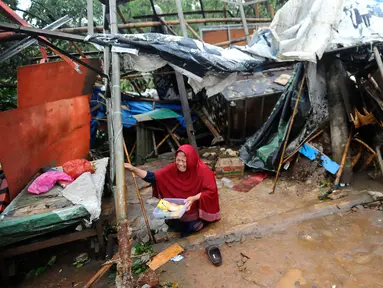 Seorang pedagang menangis usai warung kopi miliknya hancur tertimpa pohon tumbang di pinggir Jalan Raya Sawangan Depok, Minggu (09/10/20222). Hujan es disertai angin kencang yang terjadi di sejumlah kawasan di Depok pada Minggu sore mengakibatkan sejumlah bangunan dan pohon tumbang. (merdeka.com/Arie Basuki)