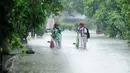 Dua anak sekolah membawa sepedanya melitasi banjir di perumahan Pondok Hijau Permai, Bekasi, Senin (20/2). Hujan berkepanjangan menyebabkan kali yang melintasi perumahan tersebut meluap. (Liputan6.com/Gempur M. Surya)
