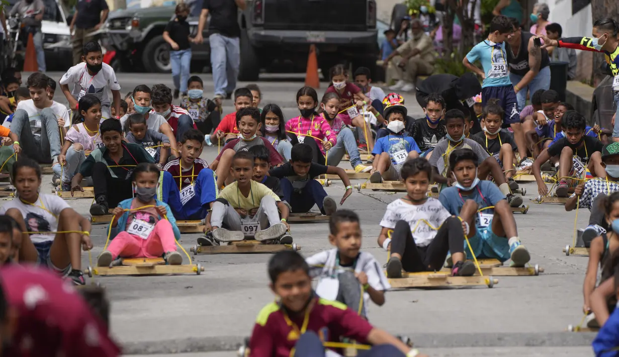 Anak-anak berpartisipasi dalam perlombaan jalanan tradisional "carruchas", sebutan untuk mobil kayu darurat di Caracas, Venezuela, Sabtu (18/12/2021). Anak laki-laki dan perempuan berusia antara 4 hingga 15 tahun berpartisipasi dalam perlombaan tersebut. (AP Photo/Ariana Cubillos)