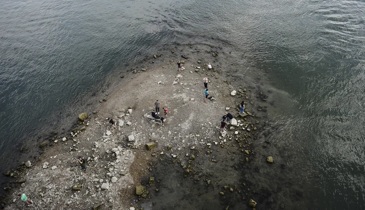 Orang-orang berdiri di ujung selatan Pulau Margaret, yang terlihat akibat rendahnya permukaan air Danube di Budapest, Hungaria (9/8/2022). Ketinggian air Sungai Danube turun satu setengah meter dalam tiga minggu di dekat Budapest, sementara prakiraan hidrologi menunjukkan bahwa tidak ada penambahan curah hujan yang diharapkan untuk saat ini. (AP Photo/Anna Szilagyi)