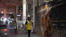 Seorang fans melintas di depan lukisan mural bintang LA Lakers, Kobe Bryant di Grand Central Market, Los Angeles, California, Selasa (26/1/2021). Lukisan dibuat untuk mengenang 1 tahun tragedi kecelakaan helikopter yang menewaskan Kobe Bryant dan putrinya, Gianna. (Getty Images via AFP/Sarah Stier)