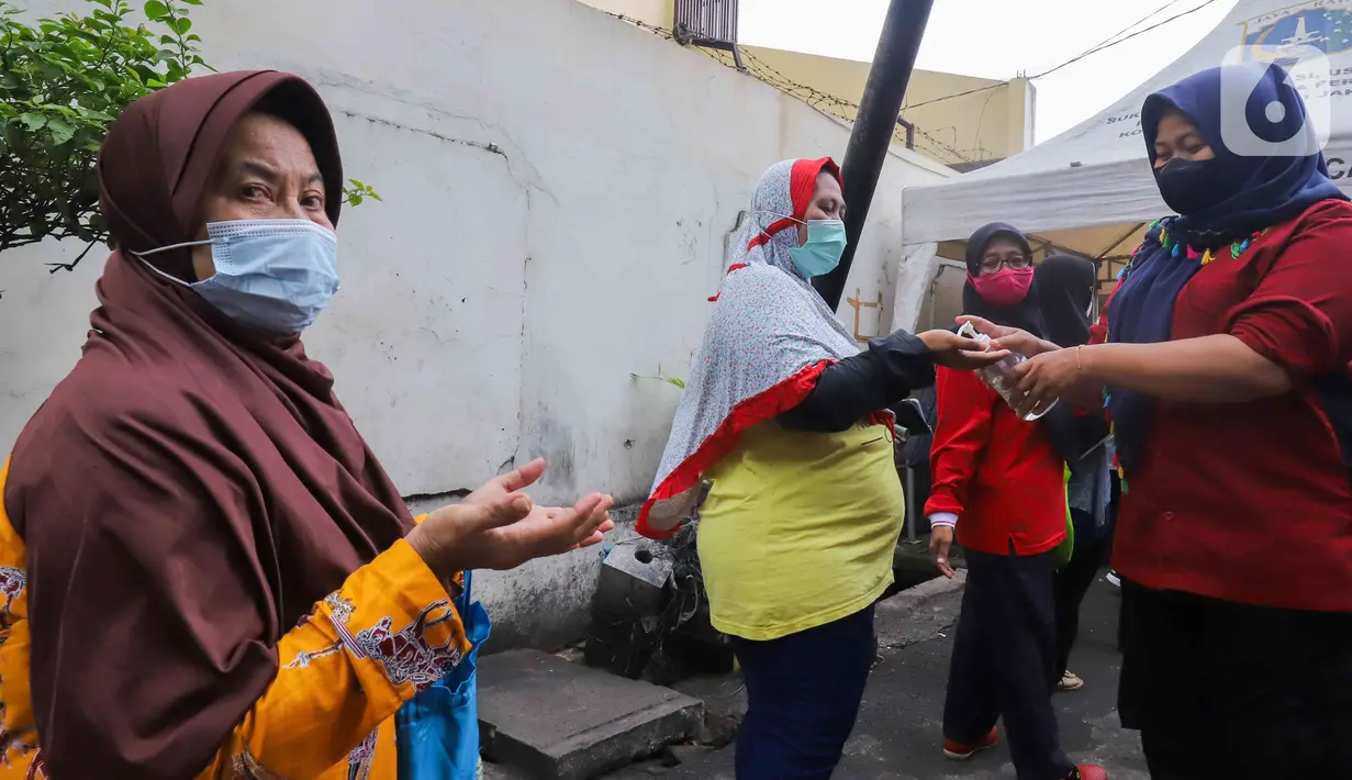 Petugas memberikan disinfektan kepada warga yang antre minyak goreng murah di depan Kantor Kecamatan Johar Baru, Jakarta, Senin (17/1/2022). Sudin PPKUKM Jakarta Pusat menggelar operasi pasar (OP) minyak goreng murah dengan harga Rp 14.000 per liter. (Liputan6.com/Herman Zakahria)