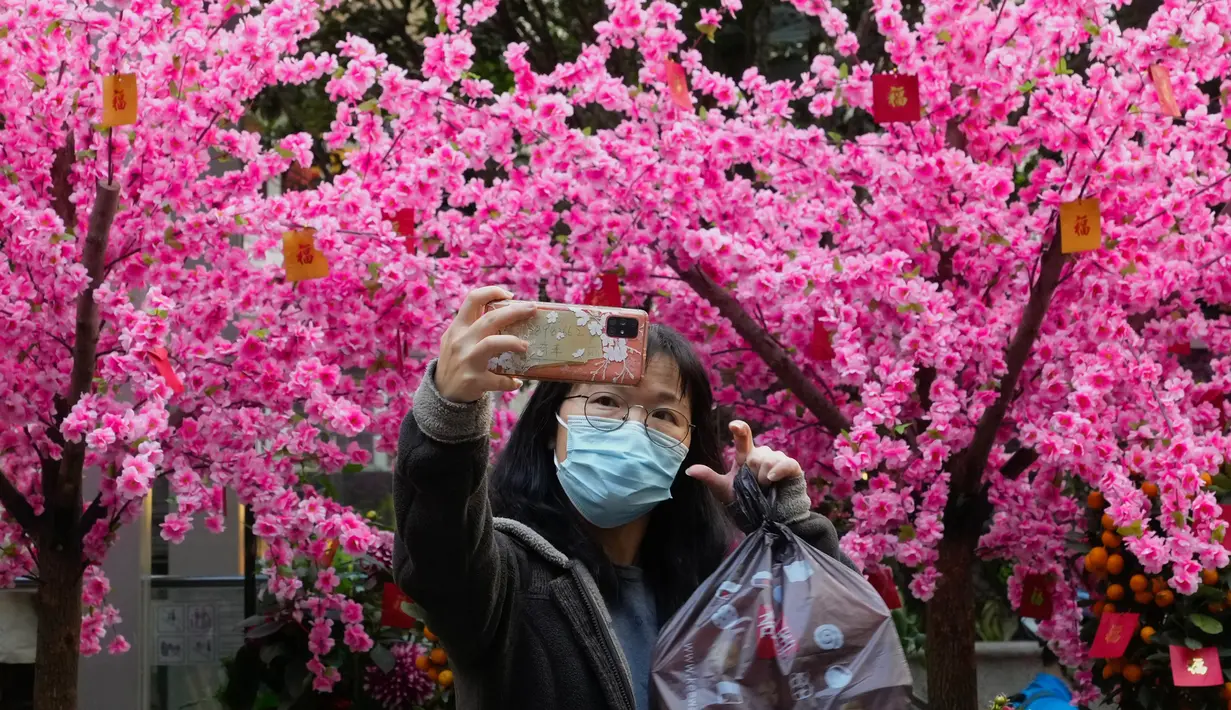 Seorang perempuan berswafoto di depan dekorasi untuk merayakan Tahun Baru Imlek di Hong Kong, Minggu (30/1/2022). Tahun Baru China atau Imlek jatuh pada 1 Februari (AP Photo/Vincent Yu)