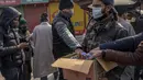 Seorang pria membagikan botol pembersih selama penguncian akhir pekan di Srinagar, Kashmir yang dikuasai India, Sabtu (15/1/2022). Pihak berwenang di bagian Kashmir India mengumumkan pembatasan penuh pergerakan yang tidak penting selama akhir pekan  untuk mengekang COVID-19. (AP Photo/Dar Yasin)