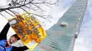 Seorang warga memberikan dukungan untuk atlet panjat tebing 'free solo' asal Amerika, Alex Honnold saat memanjat gedung Taipei 101 tanpa tali pengaman di Taipei, Minggu (25/01/2026). (AP Photo/Chiang Ying-ying)