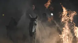 Sejumlah penunggang kuda melompati api unggun di desa San Bartolome de Pinares, Spanyol (16/1). Ritual ini merupakan cara unik menolak bala dan bahaya sepanjang 2018. (AFP Photo/Gabriel Bouys)