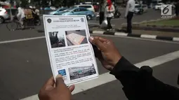Pengendaran menerima selebaran sosialisasi lajur sepeda motor di Jalan MH Thamrin, Jakarta, Senin (29/1). Pengendara sepeda motor yang melintas di luar lajur khusus tersebut akan diberi sanksi sesuai ketentuan yang berlaku. (Liputan6.com/Arya Manggala)