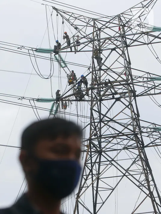 Pekerja menyelesaikan pekerjaan jaringan SUTET di Tangerang, Banten, Senin (2/1/2021). PT PLN (Persero) memiliki pasukan khusus yang terlatih melakukan pemeliharaan, perbaikan, dan penggantian perangkat isolator, konduktor maupun komponen lainnya pada jaringan listrik. (Liputan6.com/Angga Yuniar)