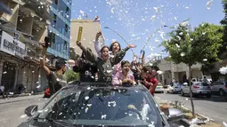Siswa SMP Palestina menyemprotkan busa dari jendela mobil saat mereka merayakan kelulusan usai mengikuti ujian akhir yang dikenal sebagai "Tawjihi" dengan nilai 99/100, di Kota Hebron, Tepi Barat (3/8/2021). (AFP/Hazem Bader)