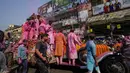 Umat Hindu berkerumun di sekitar mobil Rolls Royce 1921 yang dimodifikasi membawa patung dewa Krishna melalui bangunan bersejarah Howrah Bridge selama festival Holi di Kolkata, India, Minggu, 5 Maret 2023. (AP Photo/Bikas Das)