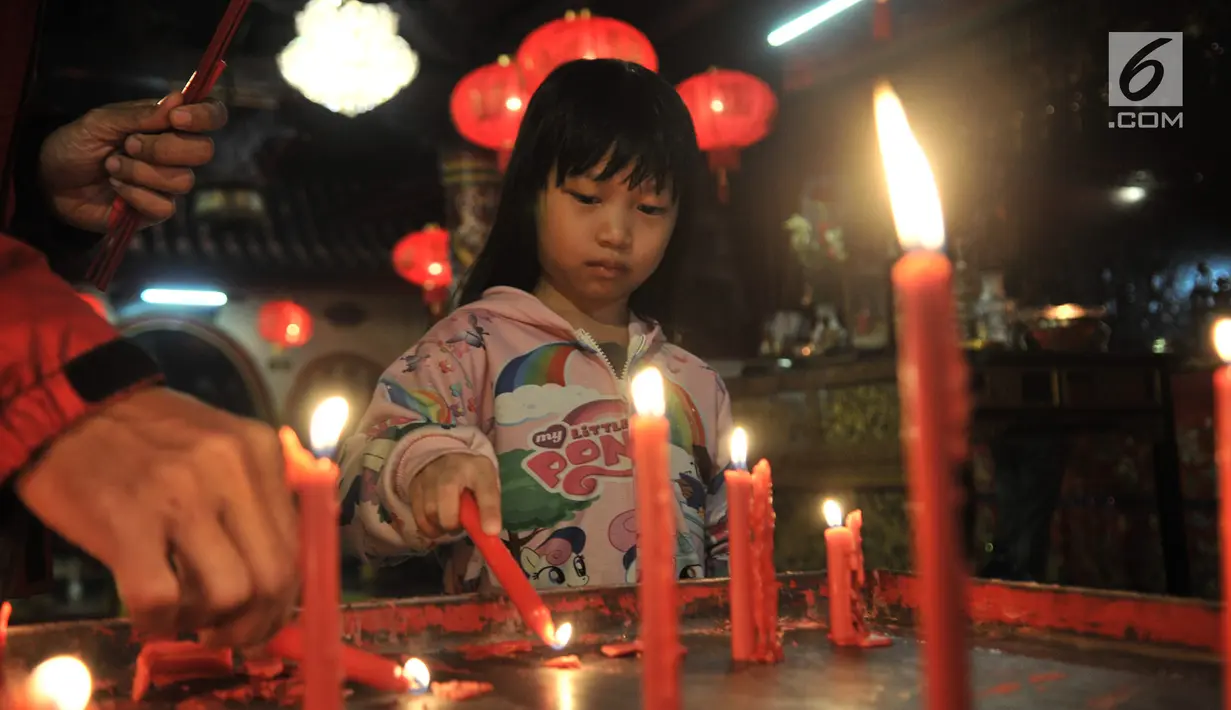 Seorang anak menyalakan lilin saat berdoa di Klenteng Boen Tek Bio, Pasar Lama, Tangerang, Kamis (31/1).  Klenteng yang dibangun tahun 1684 ini merupakan rumah ibadah yang ramai dikunjungi oleh umat Tionghoa. (Merdeka.com/Iqbal S. Nugroho)