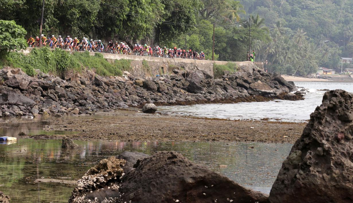 Para pebalap sepeda melintasi Pantai Teluk Bayur dalam Etape 1 Tour de Singkarak antara Painan, Kabupaten Pesisir Selatan menuju Pariaman, Sumatra Barat saat, Sabtu (3/10/2015). (Bola.com/Arief Bagus)
